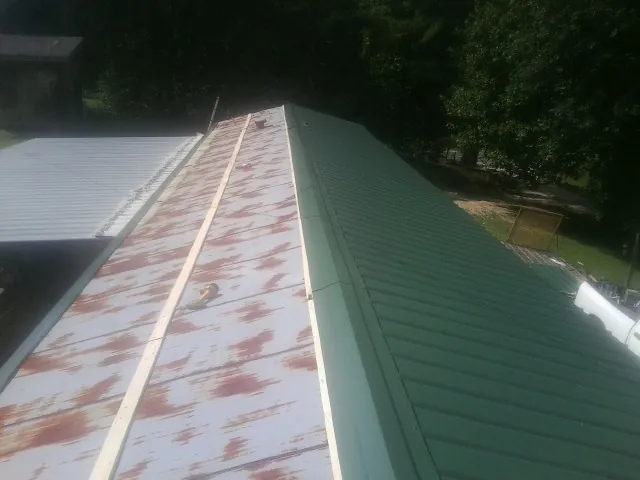 Old rusted panels beside newly installed green metal roofing — Wind Damage Roof Repair by Roofing Brothers in Colorado City