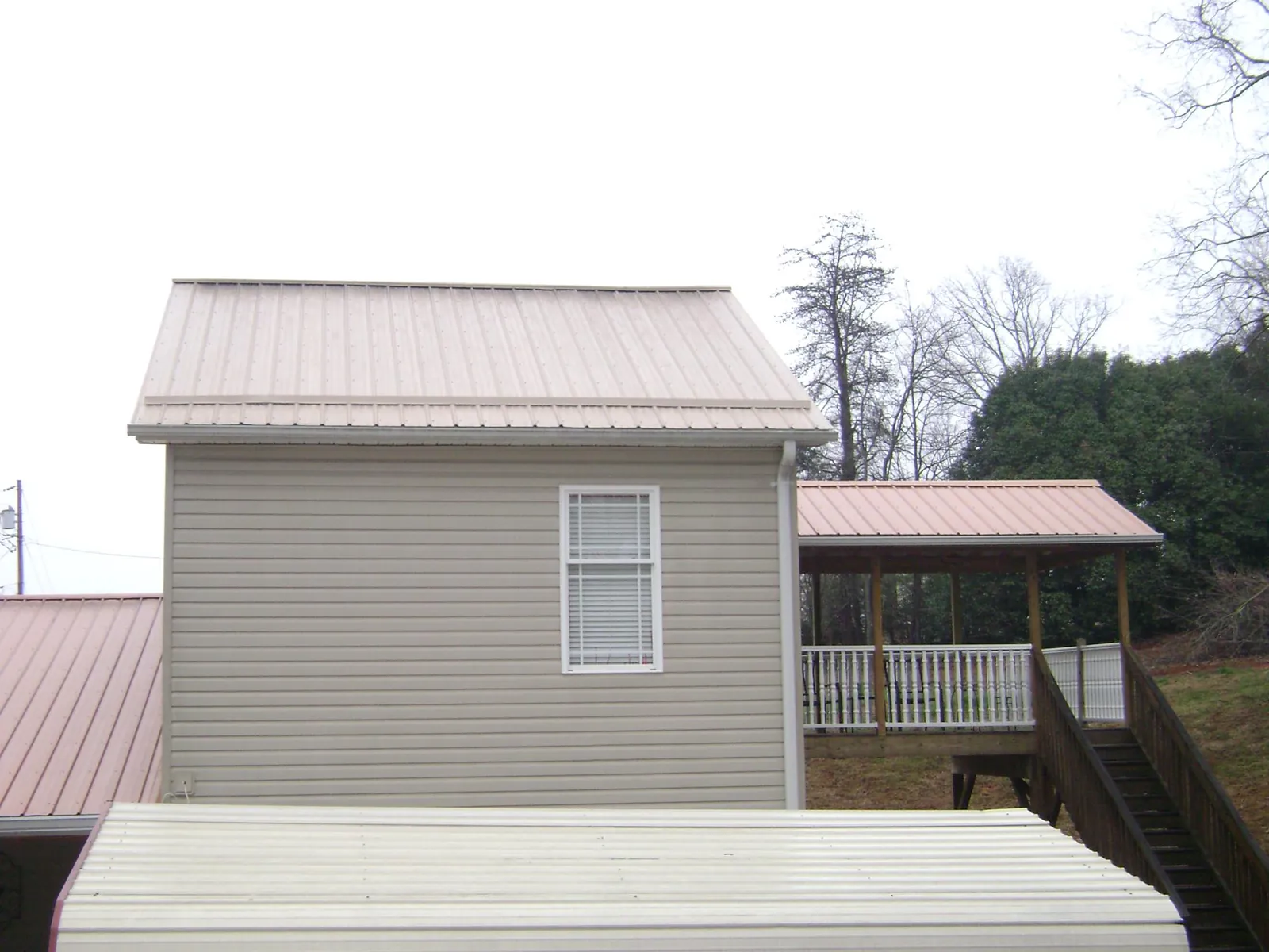 Tan metal roofs on a two story addition and attached porch, from a Roof Replacement job in Colorado City